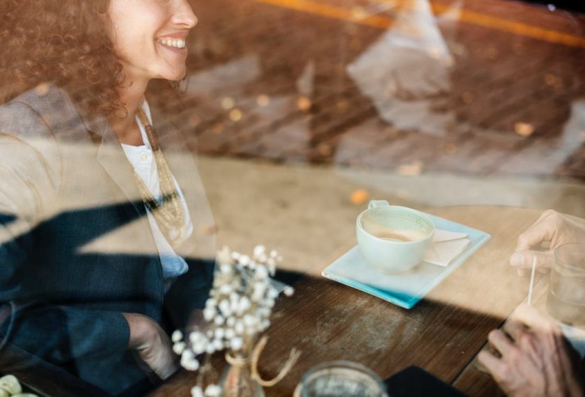 カフェのガラス越しに見える笑顔の女性