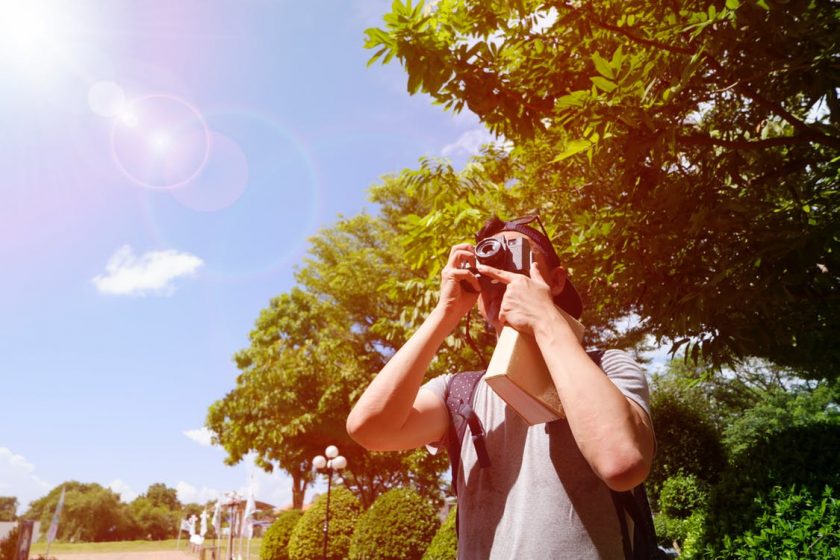太陽と青い空にカメラを向ける海外の男性